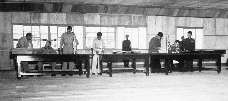 Photo: UN delegate Lieut. Gen. William K. Harrison, Jr. (seated left), and Korean People’s Army and Chinese People’s Volunteers delegate Gen. Nam Il (seated right) signing the Korean War armistice agreement at P’anmunjŏm, Korea, 27 July 1953
