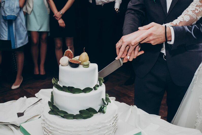 Photo: bride and groom cutting wedding cake.