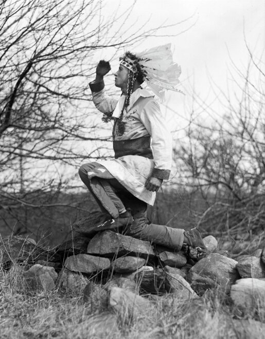 Photo: Mantasikaun posing on a stone wall. Credit: Leslie Jones Collection, Boston Public Library.