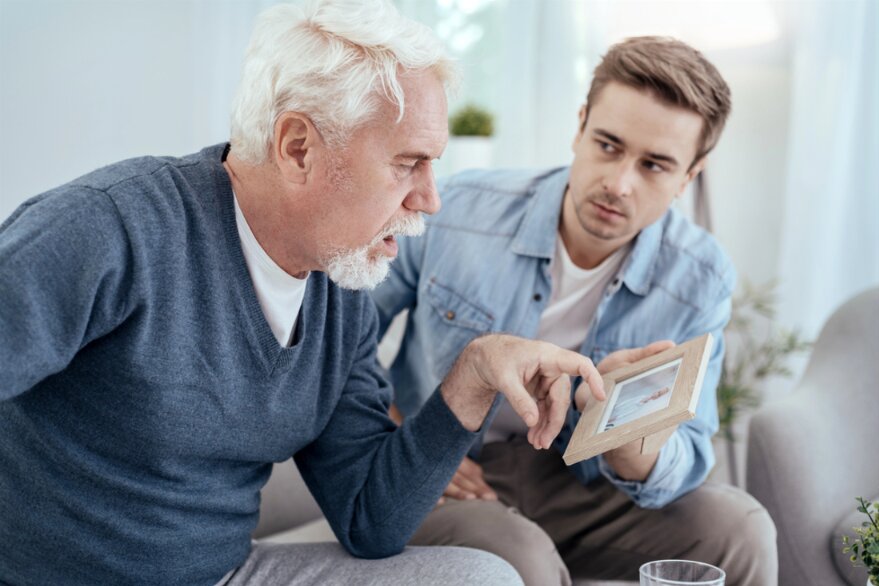 Photo: looking at a framed photo with an older male relative.